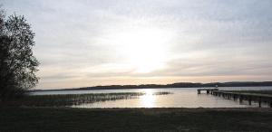 ein Dock auf einem See mit der Sonne am Himmel in der Unterkunft Bungalow Wallner in Basedow