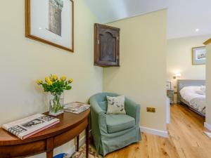 1 Bed in Lewes 79182 : غرفة بها كرسي وطاولة مع إناء من الزهور