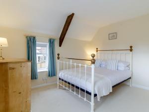 a bedroom with a white bed with blue curtains at 3 Bed in Old Hunstanton 78821 in Hunstanton