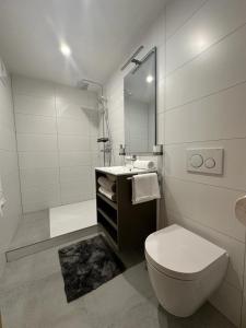 a white bathroom with a toilet and a sink at Dolomitenblick Suite in Stronach