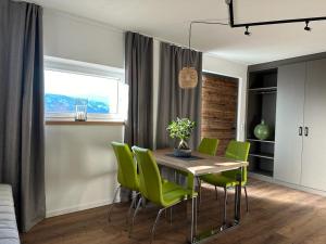 a dining room with a table and green chairs at Dolomitenblick Suite in Stronach