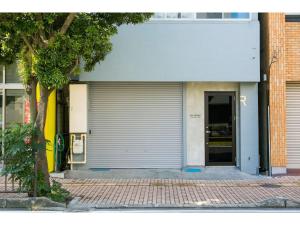 a building with a garage door next to a tree at ROI SPACE KAGOSHIMA - Vacation STAY 87818 in Kagoshima