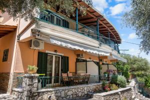 ein Haus mit einem Balkon sowie Tischen und Stühlen in der Unterkunft Rania Apartments in Agios Nikitas
