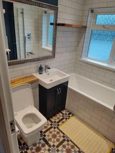 a bathroom with a sink and a toilet and a tub at Kent village house 