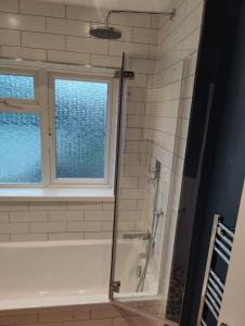 a bathroom with a shower and a tub and a window at Kent village house 