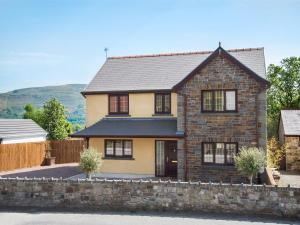 4 Bed in Ystradgynlais BN343 في Ystalyfera: منزل من الطوب كبير مع جدار حجري