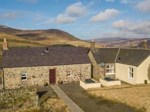 an old stone house with mountains in the background at 1 Bed in Edzell CA335 in Edzell