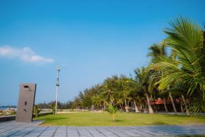 a park with palm trees and a monument at Dat Lanh Beach Resort in Lagi
