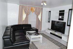 a living room with a black leather couch and a tv at Dolly Apartments in Nairobi