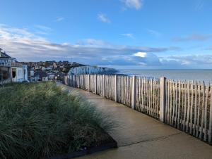 a wooden fence next to a beach with the ocean at La Nacelle, classée 3 étoiles, vue dégagée port et mer in Le Tréport