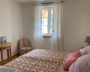 1 dormitorio con cama, ventana y silla en Ferienwohnungen Haus Rose Marie, en Grundlsee