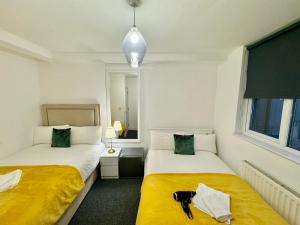 Dos camas en una habitación pequeña con sábanas amarillas. en Cosmopolitan Comfort Private Bedrooms in Euston 106, en Londres