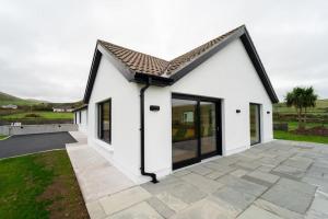 a white house with large windows and a patio at Dingle Way Rest ,Luxury holiday home in Dingle
