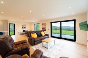 a living room with leather furniture and large windows at Dingle Way Rest ,Luxury holiday home in Dingle