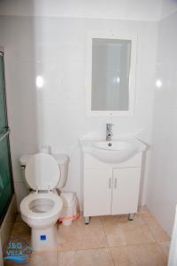 La salle de bains blanche est pourvue de toilettes et d'un lavabo. dans l'établissement J&G Villa Hotel, à Cap-Haïtien