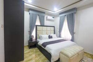 um quarto com uma cama, uma cadeira e janelas em Harlem apartment em Abuja
