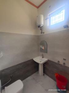 y baño con lavabo, aseo y espejo. en Gharonda Homestay, en Dogadda