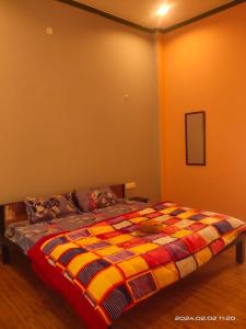 1 dormitorio con 1 cama con una manta colorida en Gharonda Homestay, en Dogadda