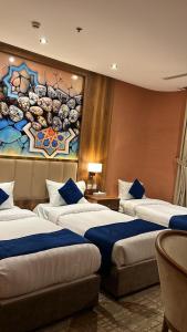 a hotel room with three beds and a painting on the wall at EWG Golden Sea Hotel Obhur in Jeddah