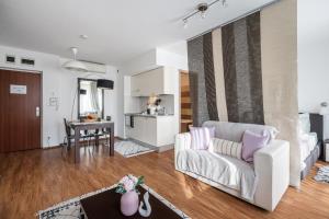 a living room with a white couch and a kitchen at Harmony Hideaway Apartment in Budapest