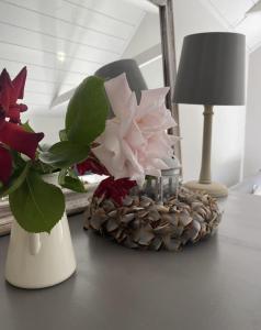 einen Tisch mit einer Vase mit Blumen und einer Lampe in der Unterkunft Mulberry Studio in Hawkhurst