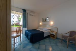 una camera con letto, tavolo e sedia di Hotel Villa Ireos a Ischia