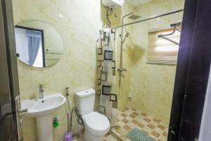 uma casa de banho com um WC, um lavatório e um espelho. em Harlem apartment em Abuja