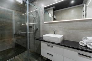 a bathroom with a sink and a glass shower at Apartament Śnieżna Melodia - z widokiem na śnieżkę, blisko stoku narciarskiego, obok Aquaparku by SpaceApart in Karpacz