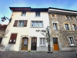 a large stone building with windows and doors at "La Petite Rochette" in Estavayer-le-Lac