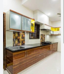 una cocina con armarios de madera y fregadero en RADHA-NIVAS, en Rohīna