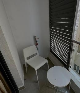 a white chair and a table in a room with a window at Cozy Apartment in Boshar in Muscat