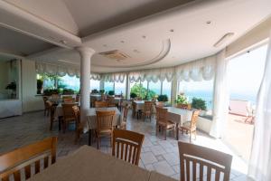 un ristorante con tavoli, sedie e ampie finestre di Hotel Villa Ireos a Ischia