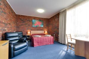 a room with a bed and a table and a chair at Enfield Motel in Adelaide