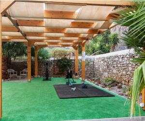 a gym with a wooden pergola and green grass at Pedi Beach Hotel in Symi