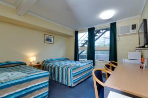 um quarto de hotel com duas camas e uma mesa e uma janela em Enfield Motel em Adelaide