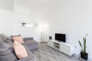 a living room with a gray couch and a tv at Home2Book Stylish & Bright Apt, Santa Cruz Center in Santa Cruz de Tenerife