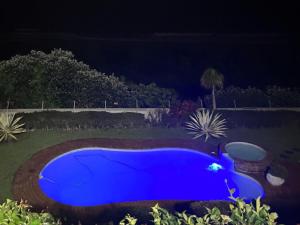 niebieski basen w ogrodzie w nocy w obiekcie Waves of Mercy w mieście Trafalgar