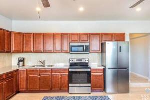 a kitchen with wooden cabinets and a stainless steel refrigerator at Charming Guest House near Chalk Sound and the Beach in Providenciales