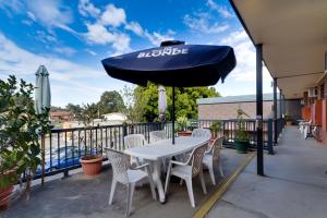 uma mesa e cadeiras sob um guarda-sol num pátio em Enfield Motel em Adelaide