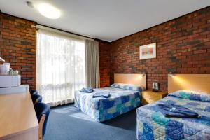 a hotel room with two beds and a brick wall at Enfield Motel in Adelaide