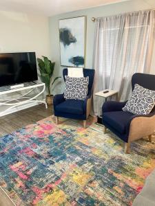 sala de estar con 2 sillas y TV de pantalla plana en Pet- & kid-equipped 2 br cottage near downtown, en Charleston