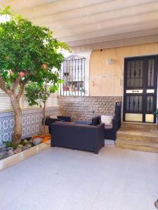 un patio con sofás y un árbol frente a un edificio en Casa con jardín, en Almería