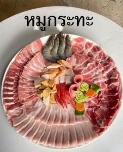 un plato de comida con carne y verduras. en Tham Ma Chard ทำมะชาด en Ban Ko Doi Tung