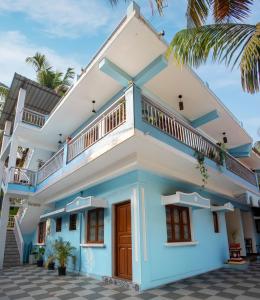 a blue and white house with a palm tree at Whiteboard Homes Siolim in Siolim