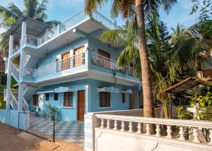 une maison bleue avec des palmiers devant elle dans l'établissement Whiteboard Homes Siolim, à Siolim