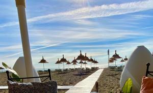 een strand met parasols en stoelen op het zand bij El Oasis - Precioso apartamento cerca de la playa in Torremolinos