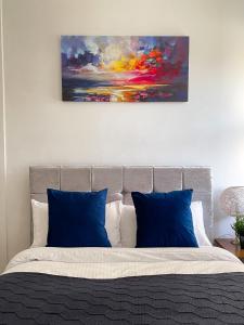 a bed with blue pillows and a painting on the wall at 3 Bedroom House in York