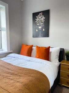 a bedroom with a large bed with orange pillows at 3 Bedroom House in York