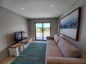 a living room with a couch and a flat screen tv at Queens Cove One Bedroom Apt 2 in Knysna