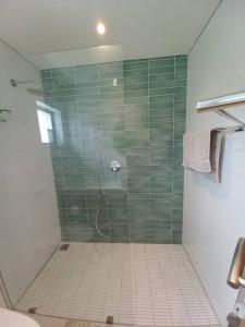 a bathroom with a shower with green tile at Queens Cove One Bedroom Apt 2 in Knysna +6 photos